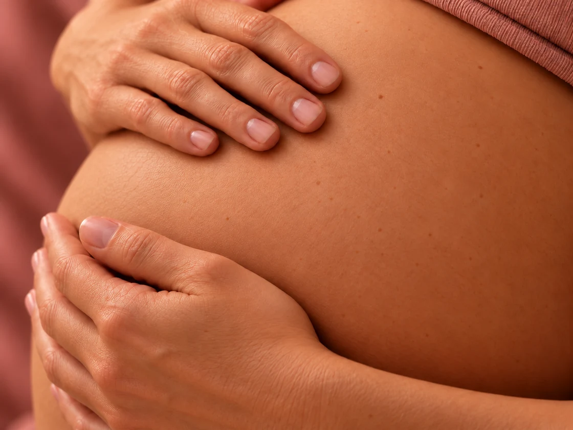 Zwei sanft aufliegende Hände am Schwangerschaftsbauch
